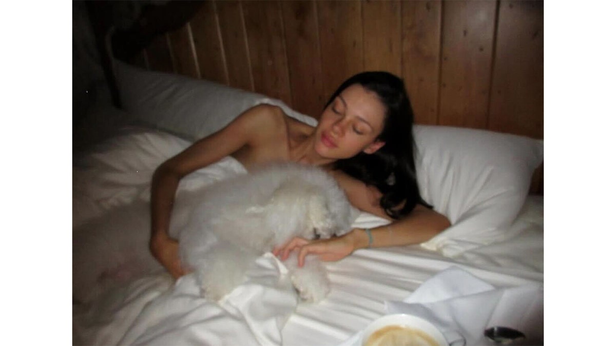 Nicola Peltz lying in bed while looking at the camera.