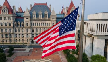 New York State Capitol building with American flag flying in front of it in plaza