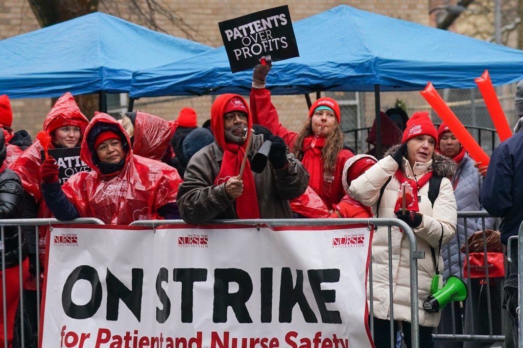 nurses under blue tents and banners saying on strike