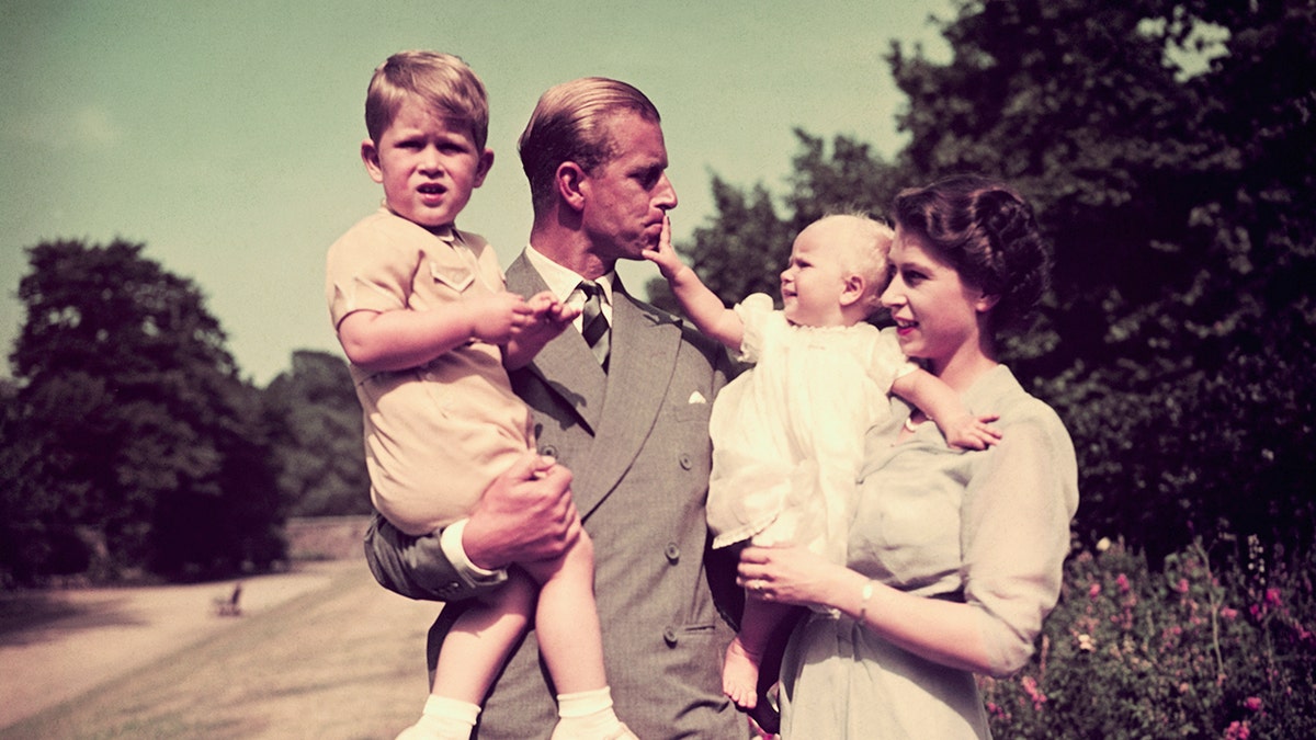 Prince Philip and Queen Elizabeth holding their children outside the palace.