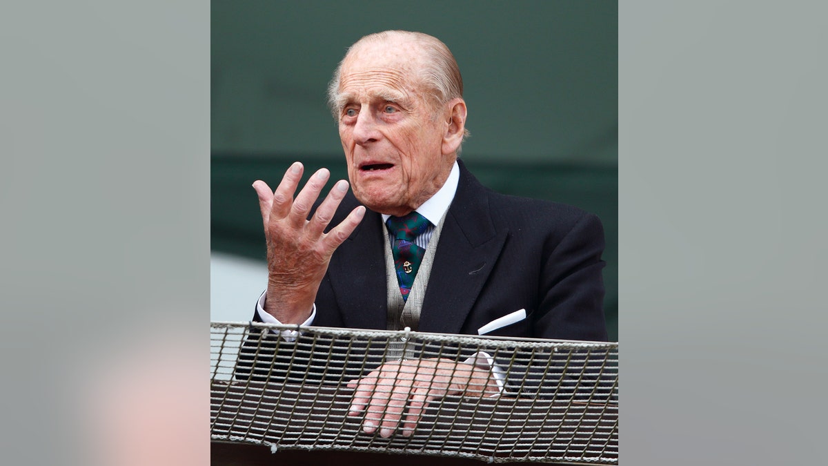 Prince Philip, the Duke of Edinburgh, making a funny face in a dark suit.