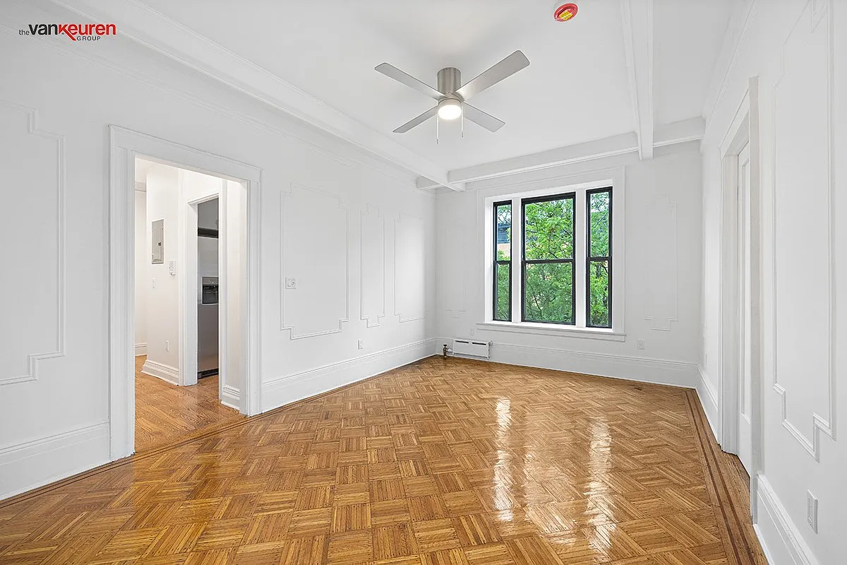 a living room with wood floor, wall moldings, and a ceiling fan