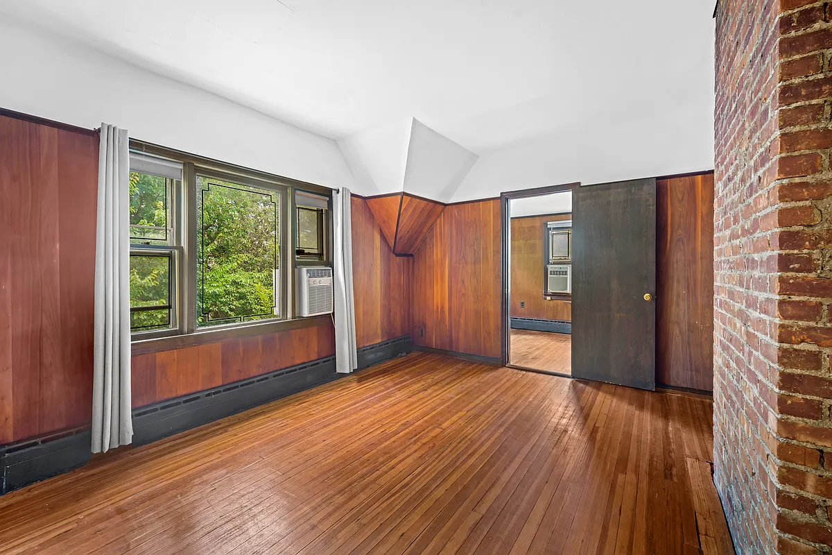 bedroom or den with paneling on walls, wood floor, baseboard heat