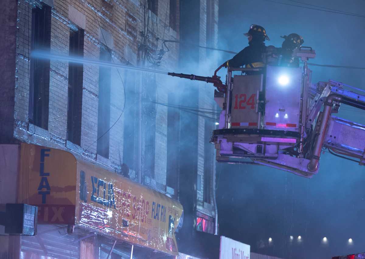 firefighters battle queens three-alarm fire pouring water into window
