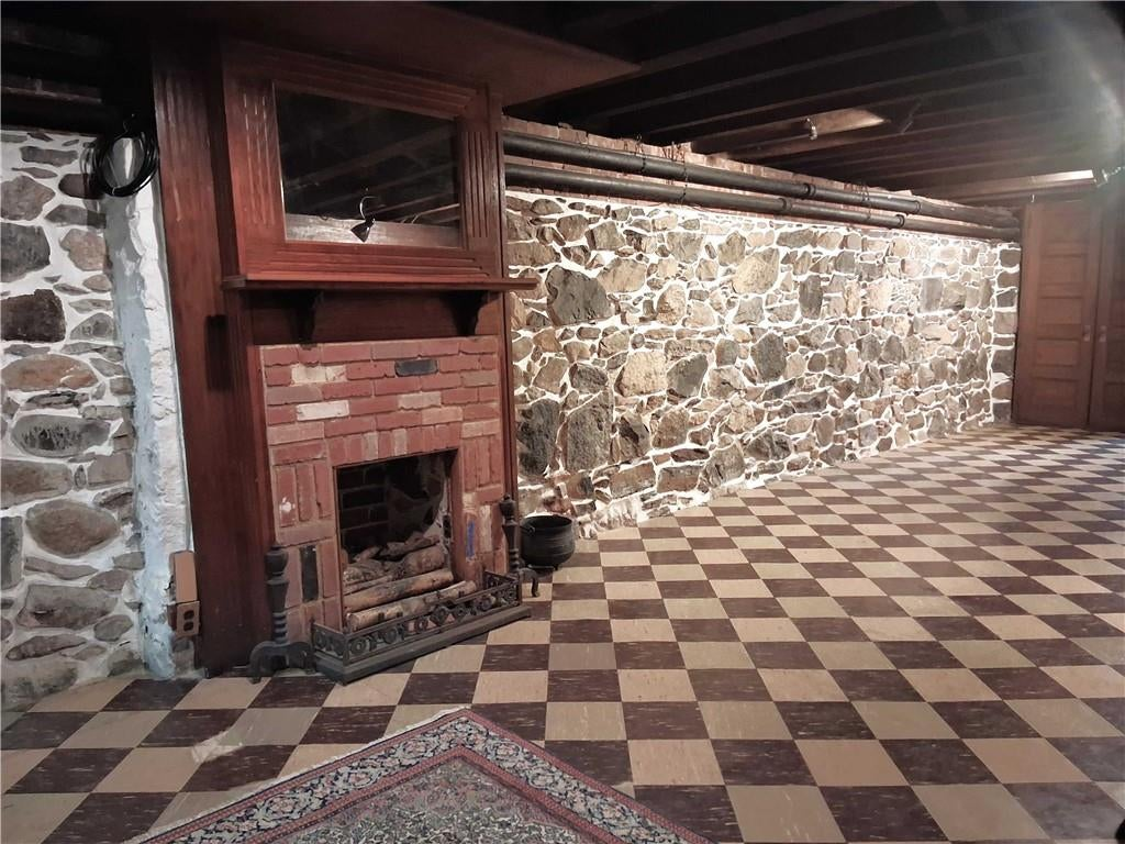 basement rumpus room with rubble stone walls and tile floor, mantel