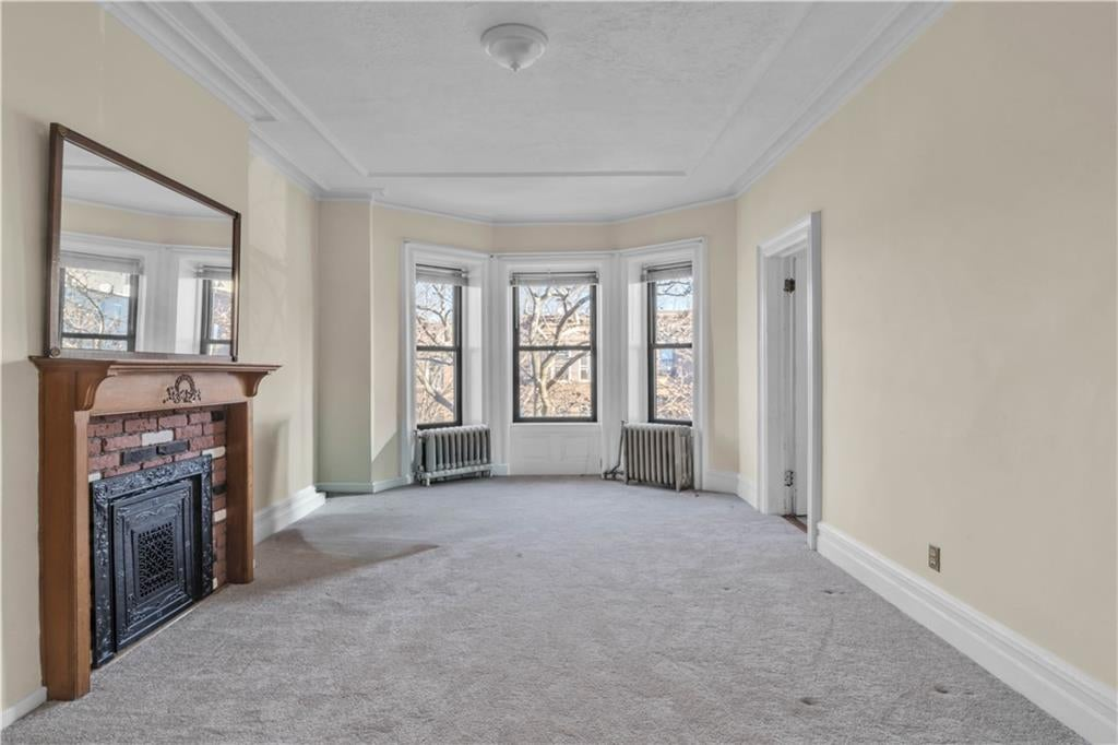 room with carpet, bay window, mantel