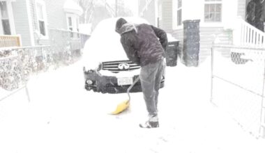 person digs their car out of a driveway in a snowstorm
