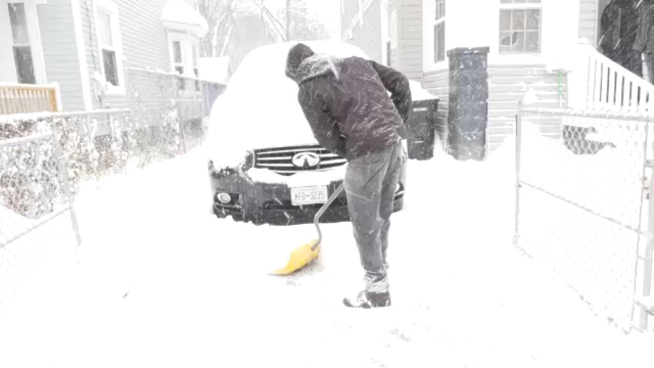 person digs their car out of a driveway in a snowstorm