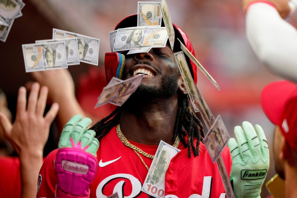 Cincinnati Reds player Elly De La Cruz in the dugout, showered with play money by teammates.