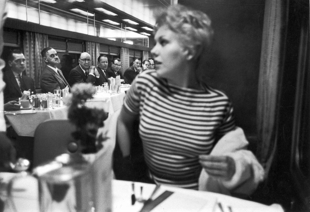"Eyes right" is executed with near-military precision by men aboard a New York-bound 20th Century Limited train as movie star Kim Novak eases into her seat in the dining car. Originally published in the March 5, 1956, issue of LIFE.