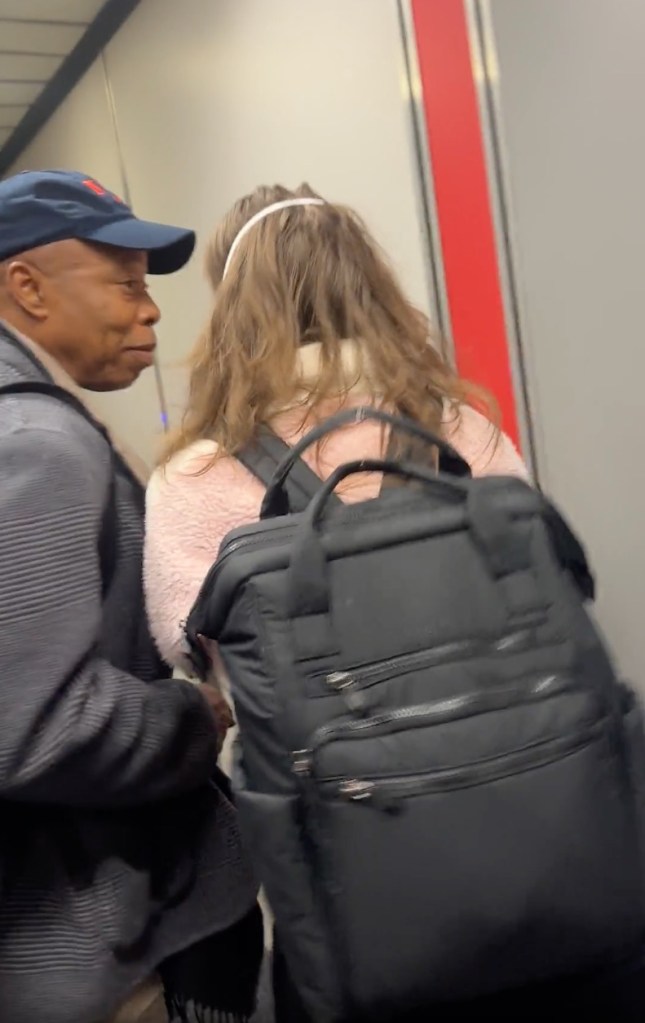 Former New York Mayor Eric Adams speaking to a fellow passenger on an airplane.