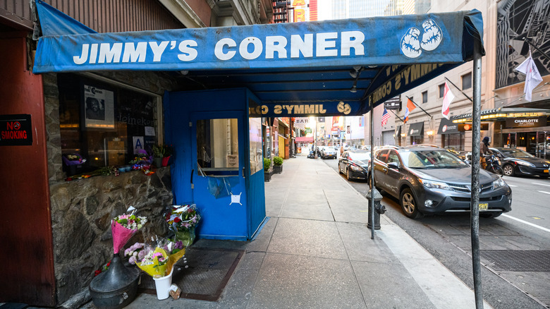 The outside of Jimmy's Corner, dive bar near Times Square, has a blue awning over the sidewalk.