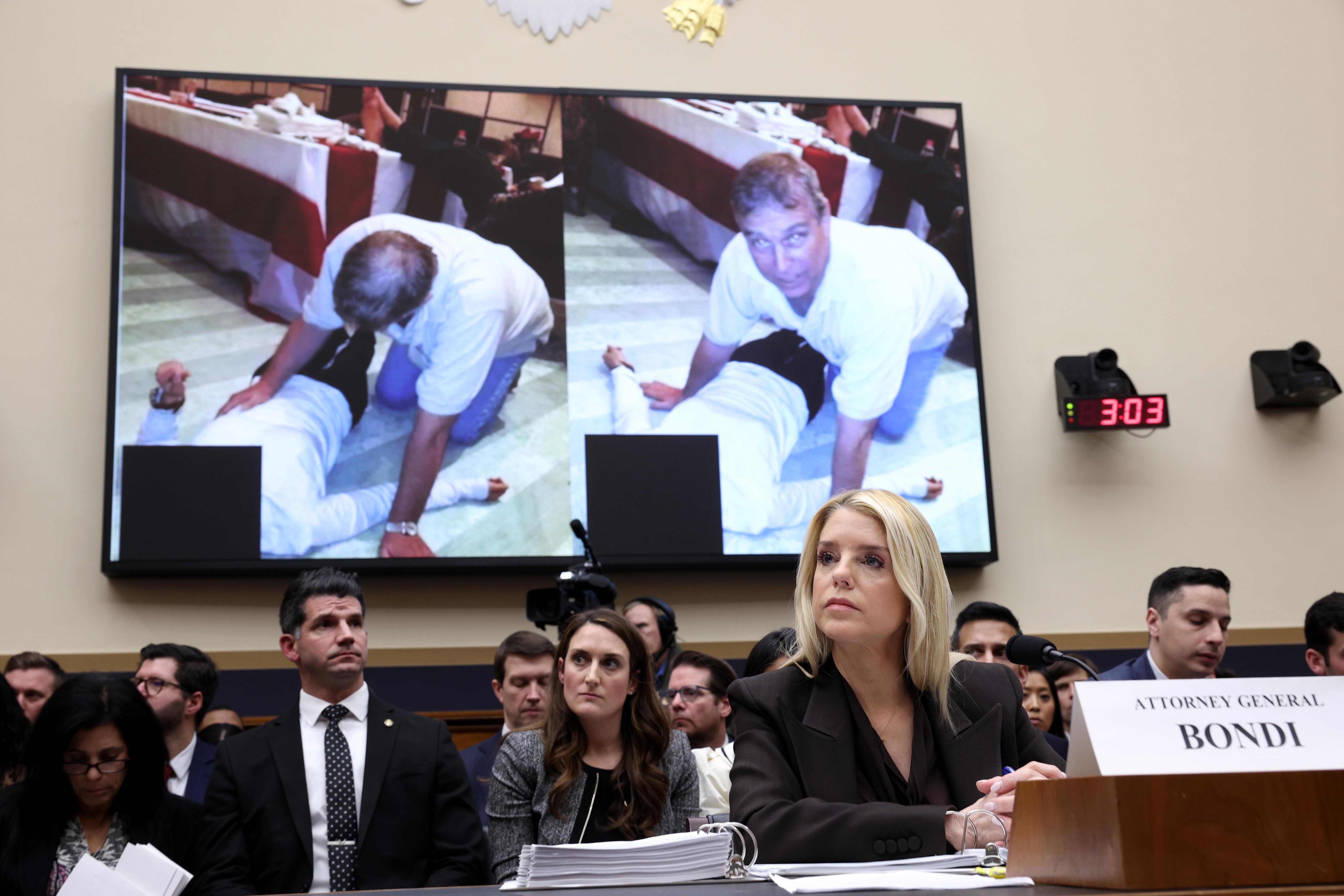 Attorney General Pam Bondi testifies at a House Judiciary hearing, with a screen displaying a photo of Andrew Mountbatten Windsor behind her.
