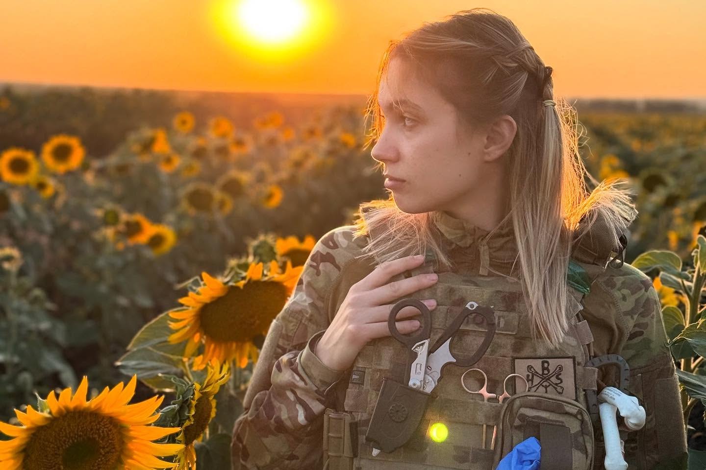 Viktoriia Honcharuk, a Ukrainian combat medic, stands in a sunflower field at sunset.