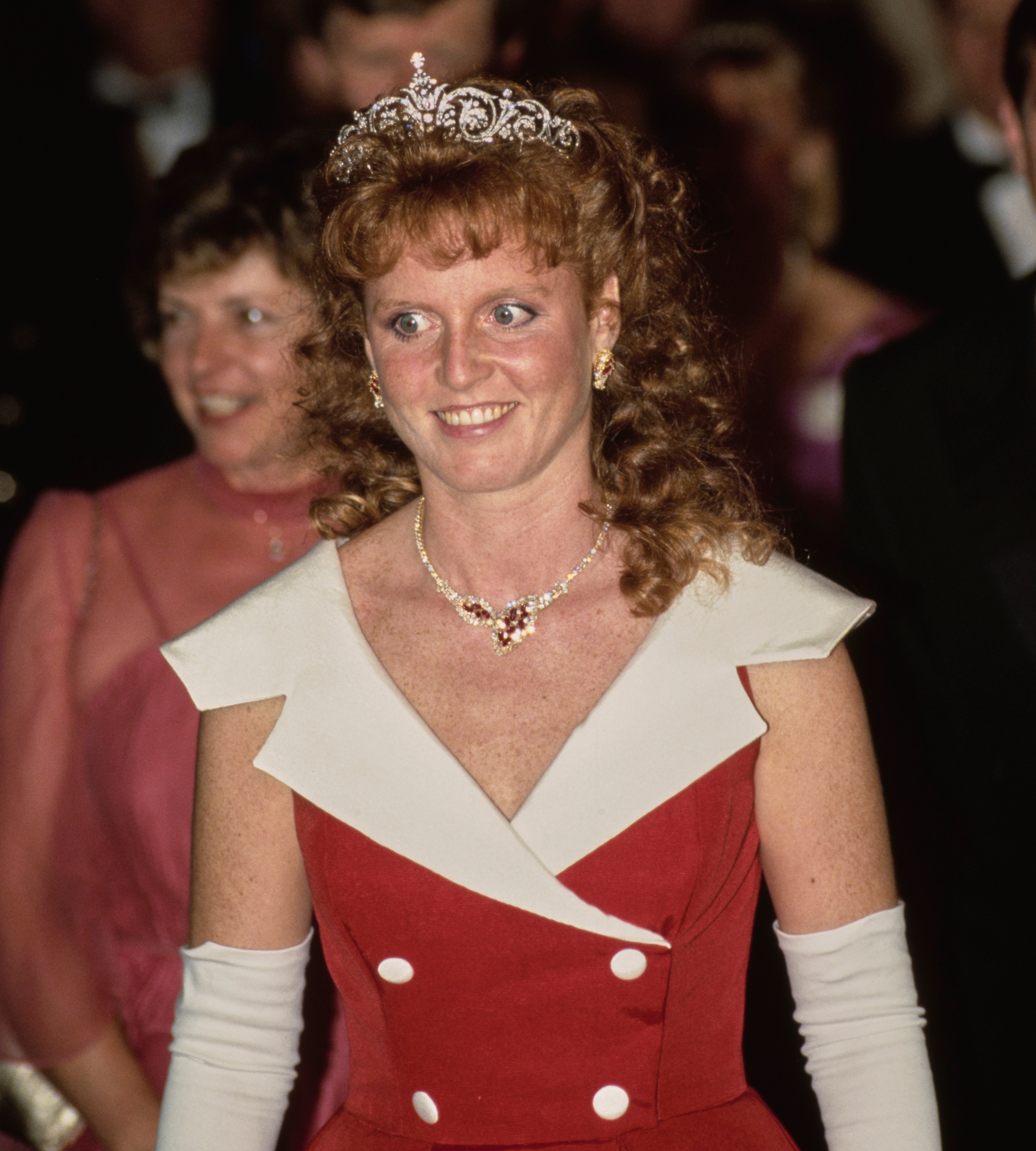 Sarah, Duchess of York, wearing a tiara, red dress with a white collar, and white gloves, attends a banquet in Toronto.