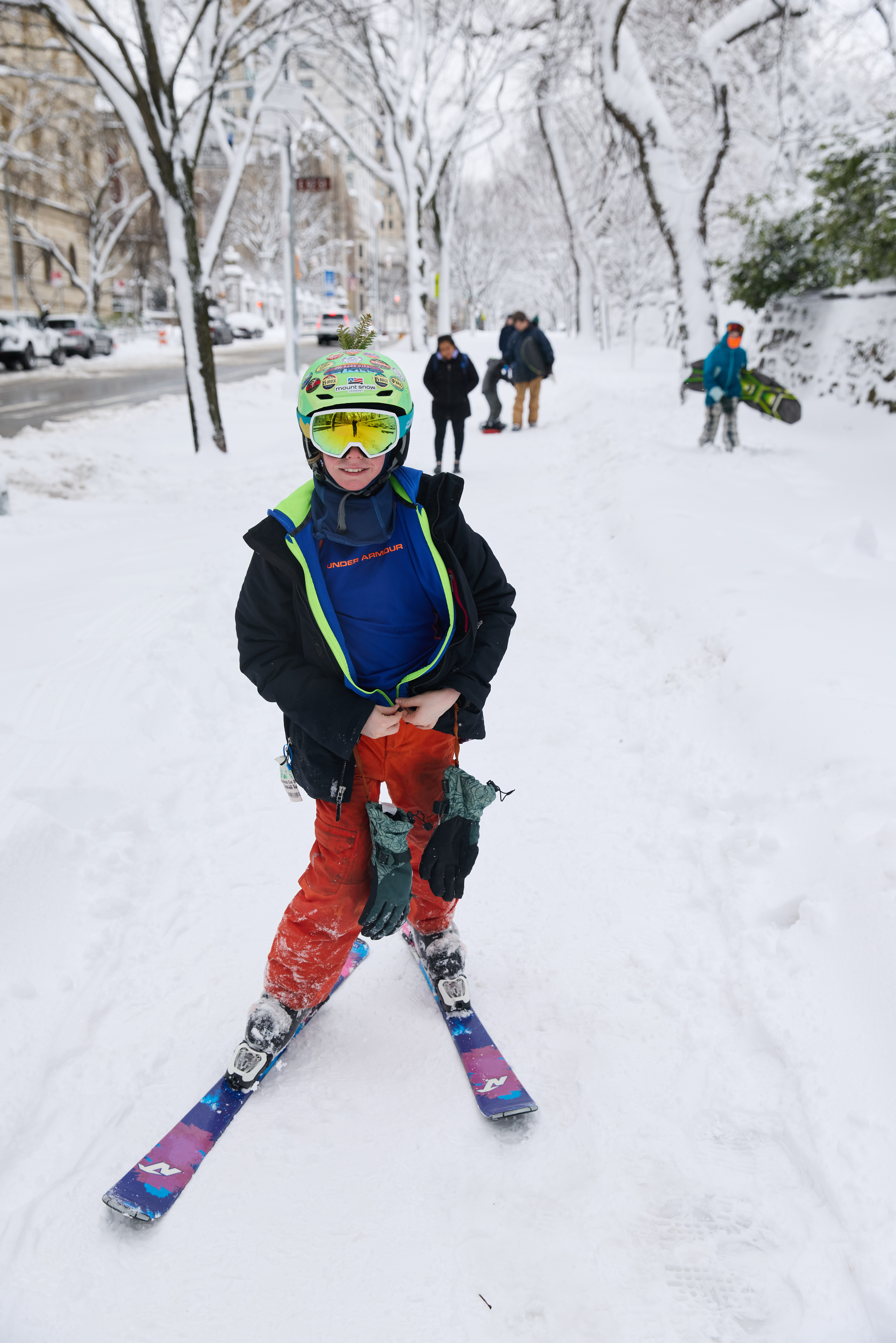 A person in ski gear stands on a snow-covered street in New York City during a blizzard.