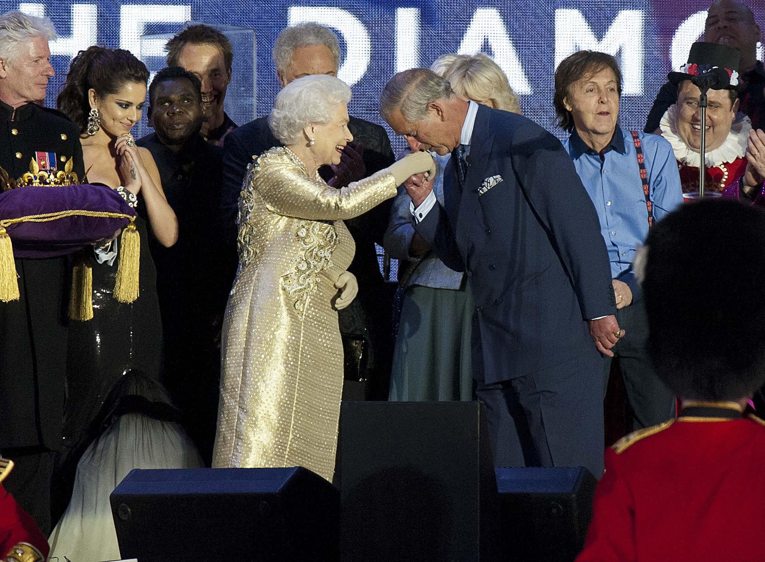 Queen Elizabeth II is greeted by her son, the Prince of Wales, as she is joined on stage with the rest of the Royal family and performers at the end of the Diamond Jubilee Concert at Buckingham Palace