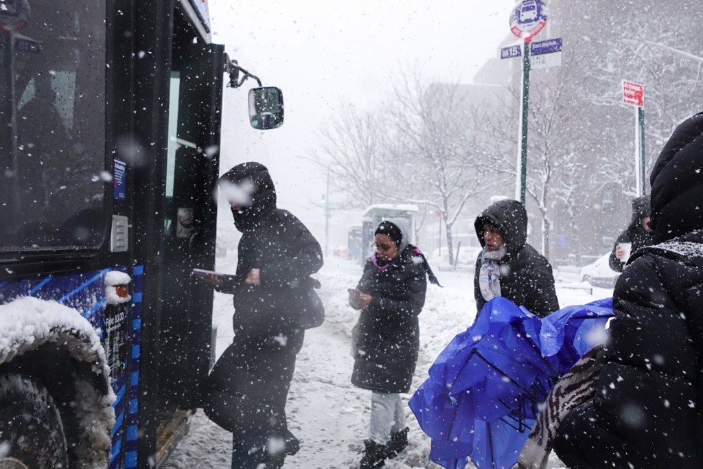 People board a bus in the East Village during a blizzard,