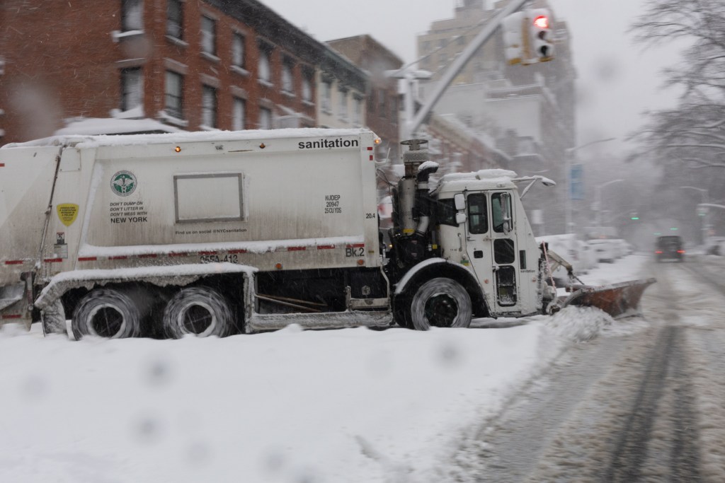 Sanitation workers plow streets in Brooklyn during a blizzard,