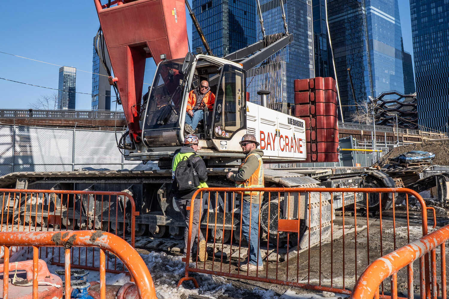 Three construction workers gather around a crane.