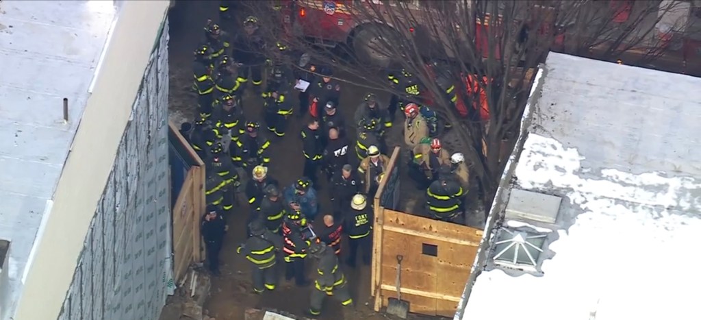 Firefighters and first responders attend to a trench collapse at a construction site.