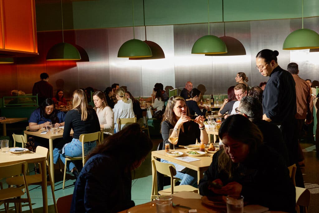 Diners sit at blond wood tables.