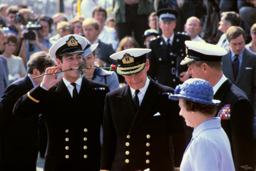 A man in a uniform holds a rose between his teeth