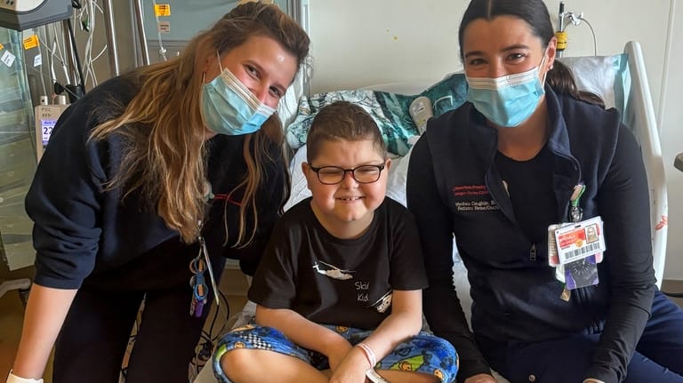 Logan Coyle, 9 years old, center, poses for a photo...