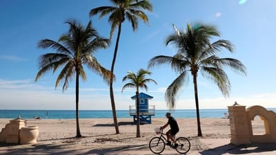 People bike on the path along Hollywood Beach in Miami,...