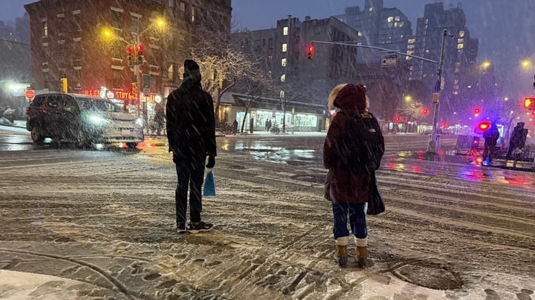 People wait to cross the corner of 20th Street and...