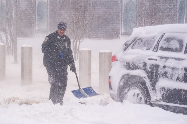 An NYPD officer shovels snow outside of the 116th Precinct stationhouse in Rosedale, Queens on Monday, Feb. 23, 2026. (Theodore Parisienne / New York Daily News)