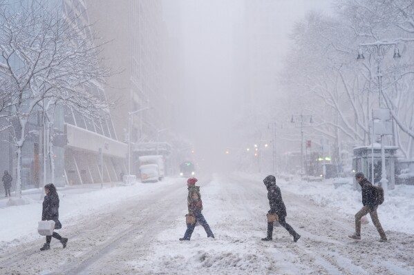 Pedestrians cross 42nd Street near Bryant Park during a snow storm, Monday, Feb. 23, 2026, in New York. (AP Photo/Seth Wenig)