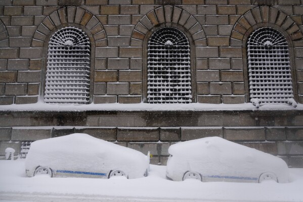 City vehicles sit parked covered in snow in lower Manhattan during a snow storm, Monday, Feb. 23, 2026, in New York. (AP Photo/Seth Wenig)