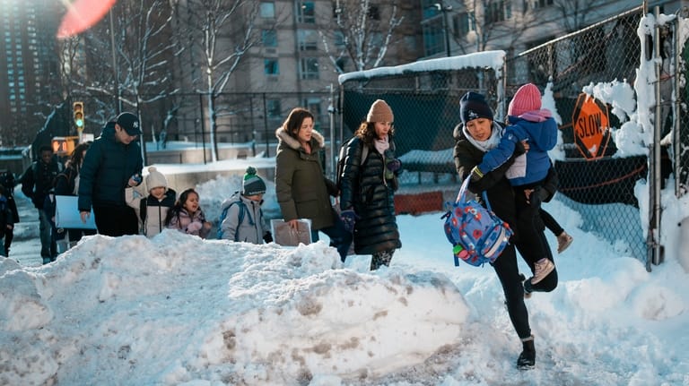 A woman carries a child over piles of plowed snow...