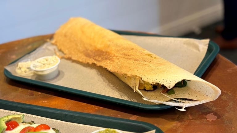 A massive dosa is stuffed with curry chutney chicken.