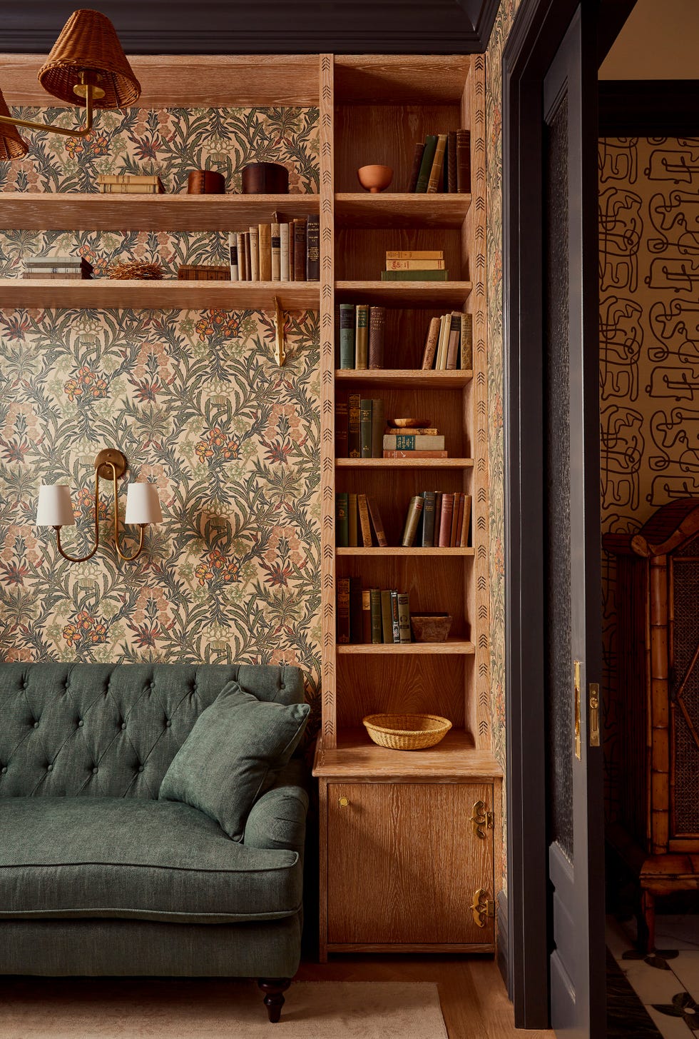 Cozy reading nook with a green couch, shelves of books, and decorative wallpaper.