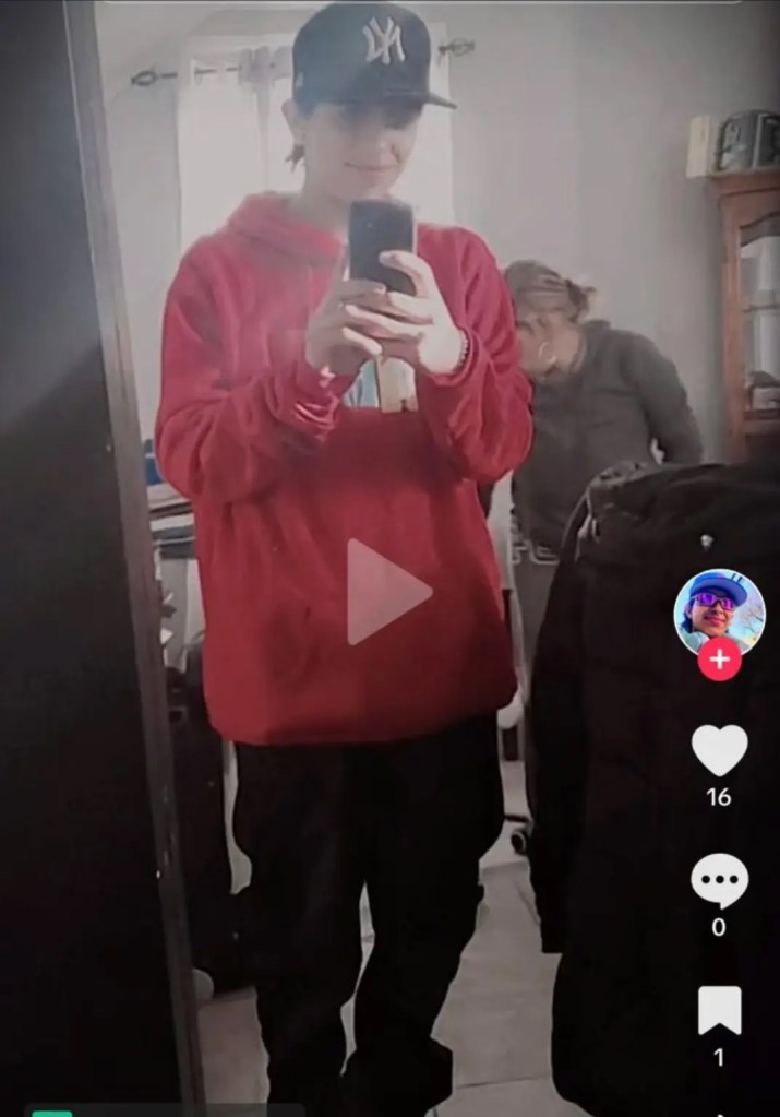 Davi Vidal in a red hoodie and Yankees cap, taking a mirror selfie.