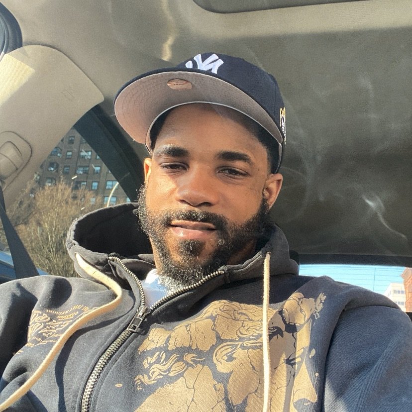 Hassan Brown wearing a dark hoodie and a dark baseball cap.