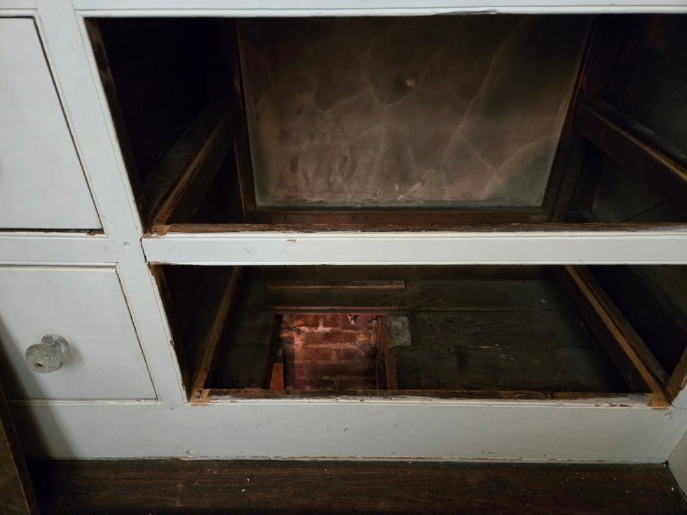 interior of a cabinet showing empty shelves and a brick wall in the background