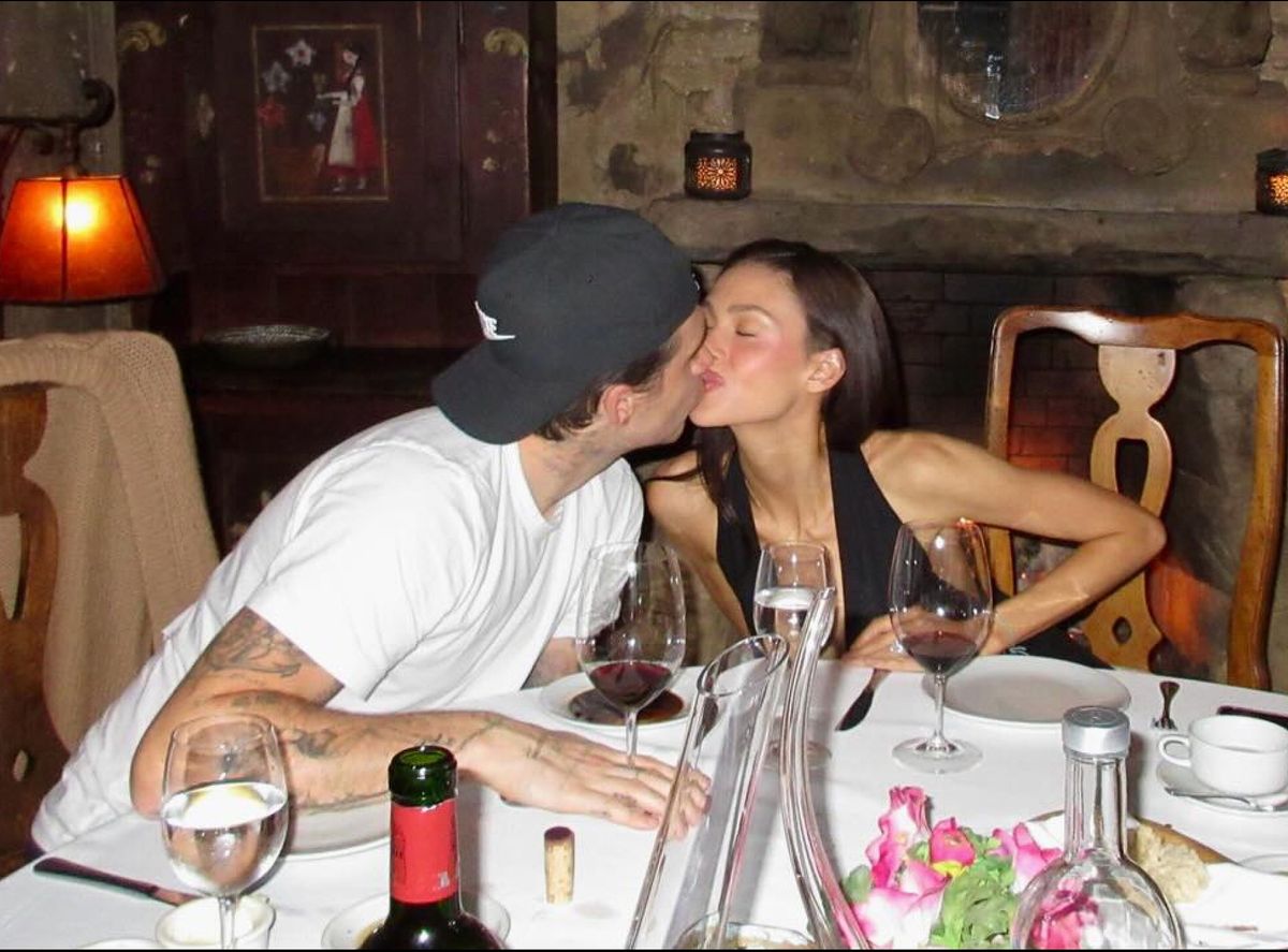 Brooklyn Beckham and Nicola Peltz kissing at a dinner table