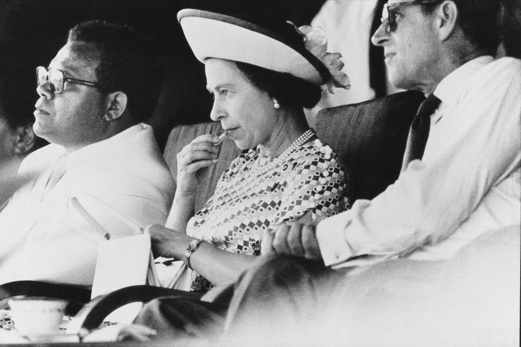 Queen Elizabeth II re-touching her lipstick in black and white 