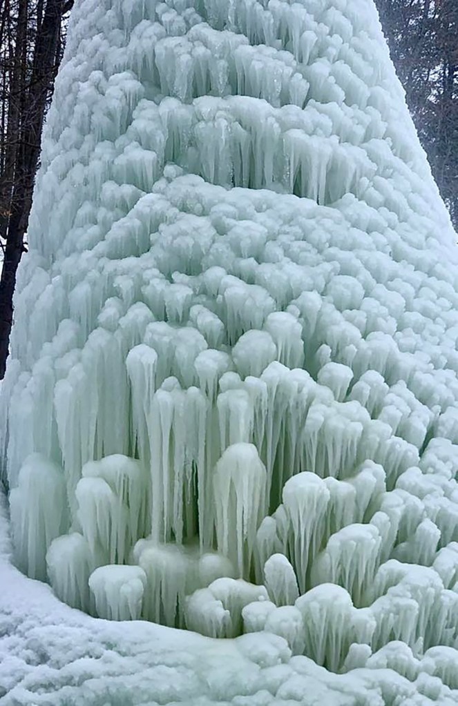 A cone-shaped structure of ice, resembling a volcano, with icicles covering its surface.