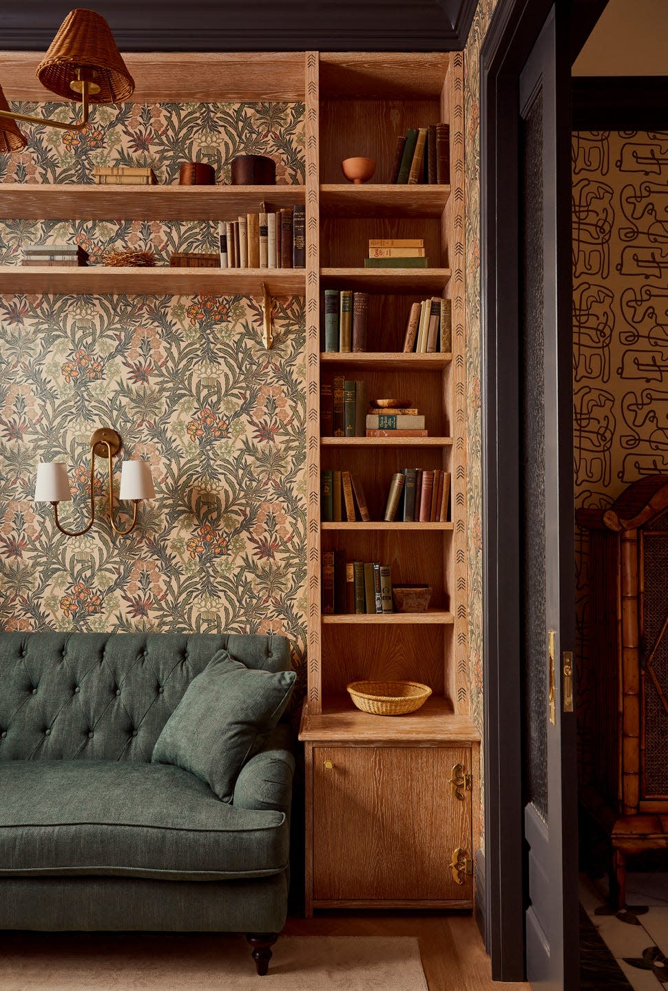 Cozy reading nook with a green couch, shelves of books, and decorative wallpaper.