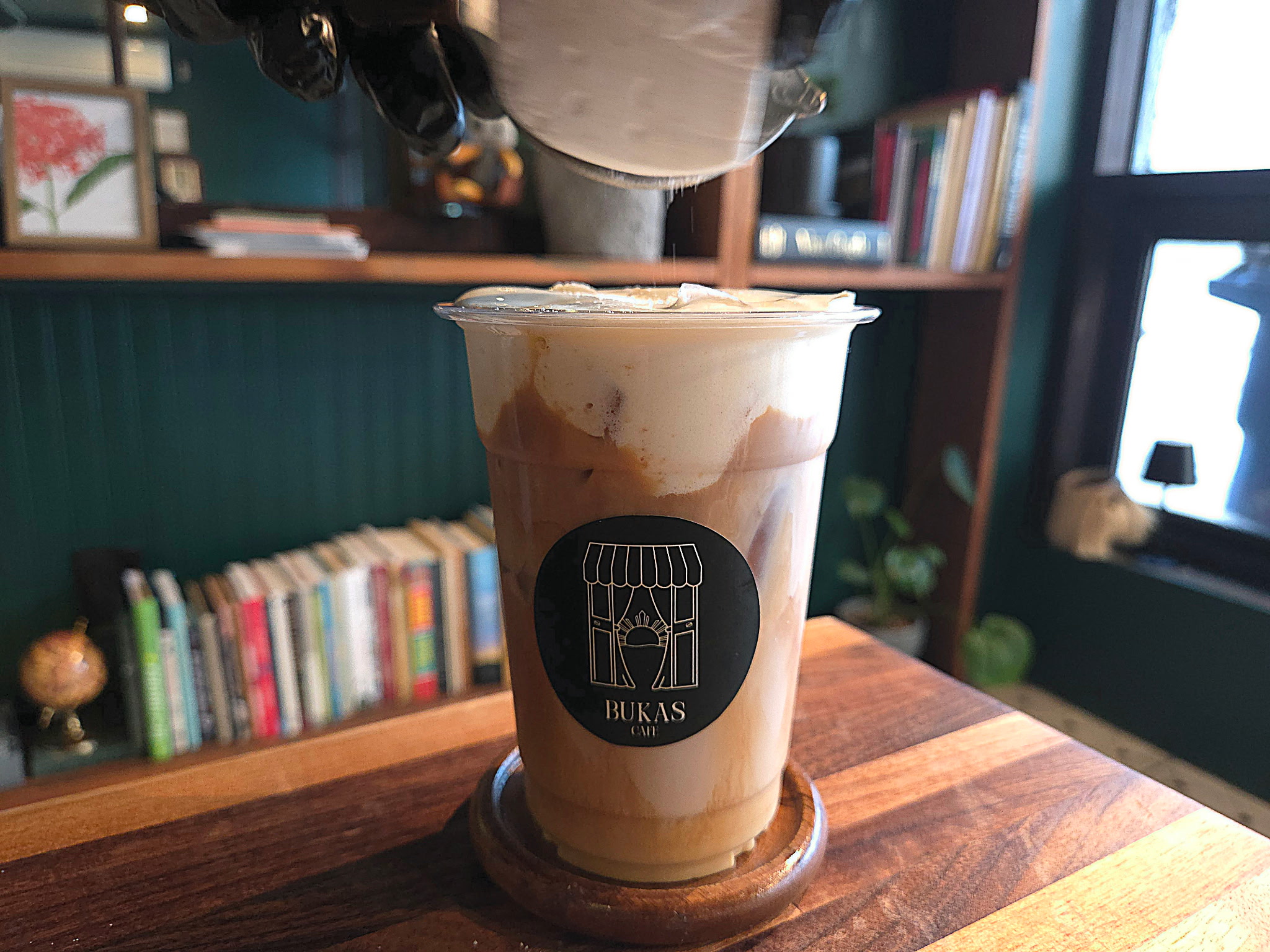 Someone sifting powder onto a drink.