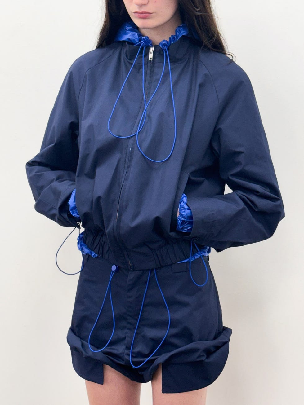 Model wearing a navy blue jacket and matching shorts with blue drawstrings.