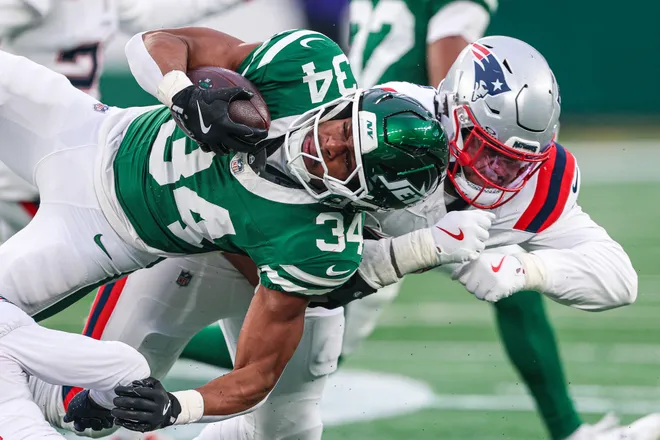 Dec 28, 2025; East Rutherford, New Jersey, USA; New York Jets running back Kene Nwangwu (34) is tackled by New England Patriots defensive tackle Jeremiah Pharms Jr. (98) during the second half at MetLife Stadium. Mandatory Credit: Vincent Carchietta-Imagn Images