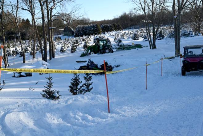 Snowmobile collision scene taped off with caution tape in a snowy field.