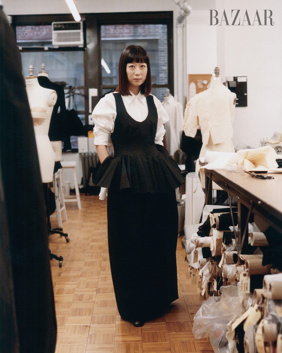fashion designer in a workshop wearing a black peplum dress