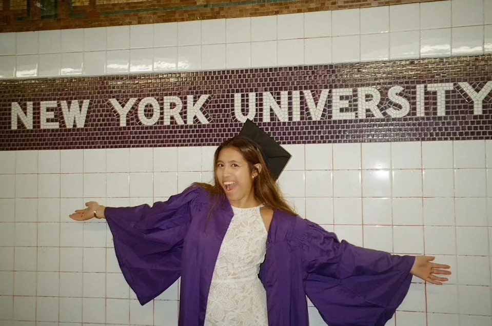 the author in her college graduation gown under a sign that reads new york university