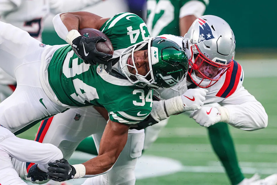 Dec 28, 2025; East Rutherford, New Jersey, USA; New York Jets running back Kene Nwangwu (34) is tackled by New England Patriots defensive tackle Jeremiah Pharms Jr. (98) during the second half at MetLife Stadium. Mandatory Credit: Vincent Carchietta-Imagn Images